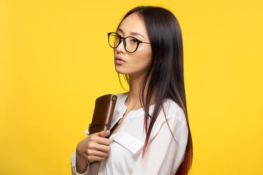 asian woman with glasses notepad holding pen elegant style yellow background. High quality photo