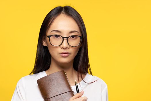 pretty brunette in white shirt holding notepad with pen office yellow background. High quality photo
