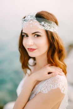 The bride by the sea looks into the frame with her hand on her shoulder, close-up . High quality photo