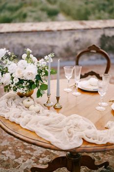 A close-up of a wooden table decorated for a wedding dinner.