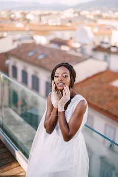 A beautiful African-American bride in white wedding dress, touches her face in vintage gloves. Fine-Art wedding in Florence, Italy