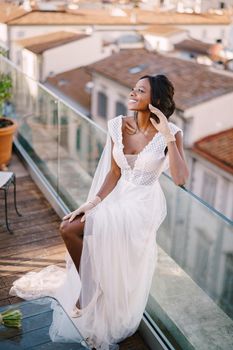 A beautiful African-American bride in white wedding dress, touches her face in vintage gloves. Fine-Art wedding in Florence, Italy