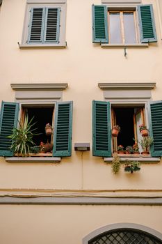 Facade of a residential building in Florence, Italy, with green wooden shutters.