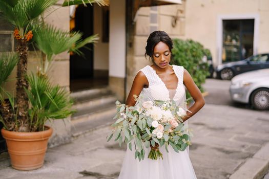 African-American bride in white dress and long veil. With a lush bouquet of the bride in her hands. Wedding in Florence, Italy.