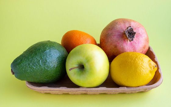 A small collection of fresh fruits in eco-friendly packaging on a yellow background.