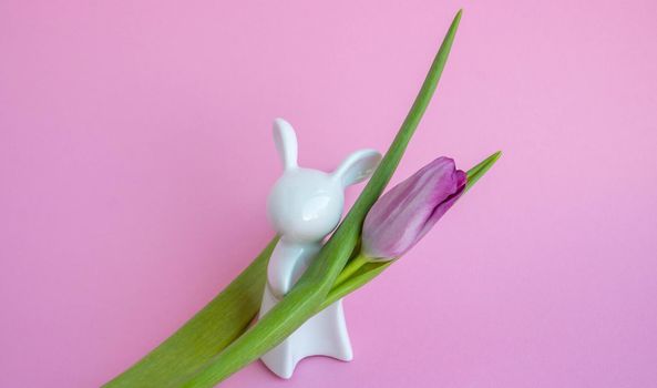 Easter bunny and lilac tulips on pink background, Easter celebration concept.