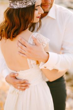 The bride and groom tenderly hug , the groom put his hands on the back of the bride . High quality photo