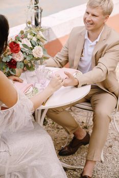 The bride and groom sit at tables on the banks of the Grand Canal and hold hands in Venice, Italy. The most romantic place on earth. Waiting for a romantic dinner for two.