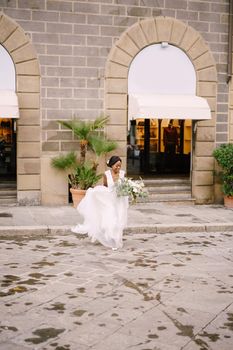 African-American bride in a white dress with a long veil and bouquet in hand. Wedding in Florence, Italy.