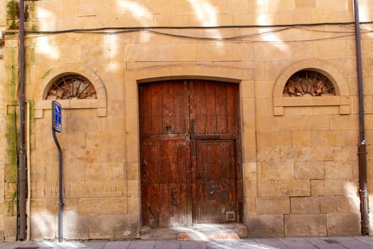 Detail of an old wooden door and two windows in a stone facade