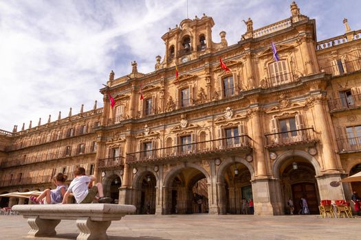 Two children sitting in a bench in front of Salamanca's City Hall at Plaza Mayor