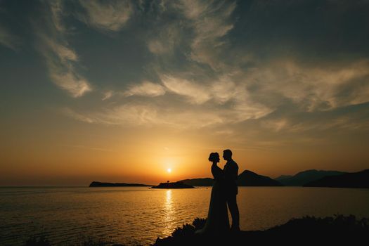 The bride and groom are embracing on the seashore at sunset and look at each other . High quality photo