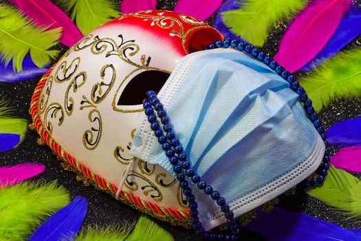 Mardi Gras carnival mask and surgical facemask with bead string tears and colorful feathers concept