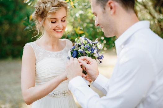 The groom puts a ring on the bride's finger during the wedding ceremony, the bride holds a bouquet and smiles . High quality photo