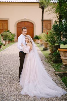 Wedding in Florence, Italy, in an old villa-winery. The young couple cuddles and looks into the camera.