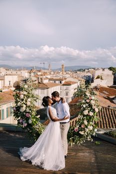 Interracial wedding couple. Destination fine-art wedding in Florence, Italy. A wedding ceremony on the roof of the building, with cityscape views of the city and Cathedral of Santa Maria Del Fiore