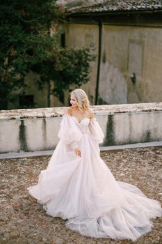 Wedding at an old winery villa in Tuscany, Italy. Bride in a white dress with bare shoulders and sleeves.