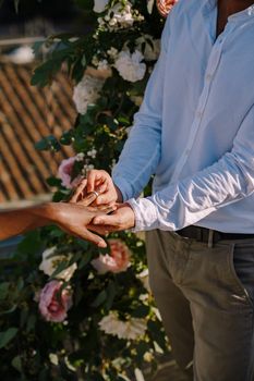 Interracial wedding couple - African-American bride and Caucasian groom. Groom puts a ring on brides finger. Destination fine-art wedding in Florence, Italy. Wedding ceremony on the roof of building