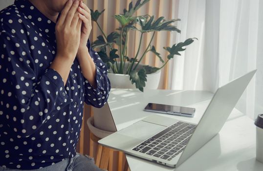 Young woman looking the laptop worried or thoughtful.Thinking about solution for the problem.Work at home advice to stop COVID-19 spreading.