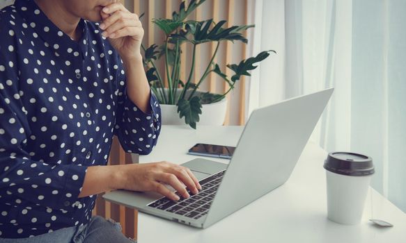 Woman using laptop and thinking about problem solution.Stay at home and work from home concept during Coronavirus pandemic.