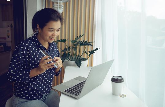 Businesswoman having conference call via laptop and phone.Stay at home and work from home concept during Coronavirus pandemic.