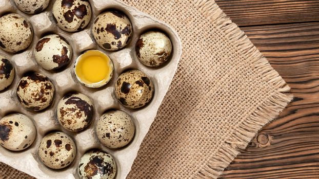 Quail eggs in cardboard packaging on a wooden table, copy space, horizontal banner, flatlay.