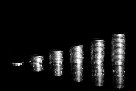Growing money graph on a row of coin and pile of baht coins stack  isolated on black background. Finance business.