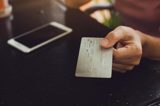 Woman hands holding smart phone with credit card for Online shopping.