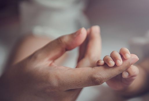 Newborn baby holding mother's hand.