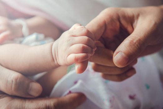 Newborn baby holding mother's hand.