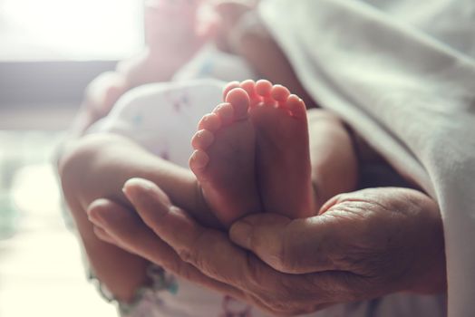 Parent is holding small infant. Baby's foot is in focus.