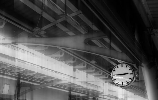 The clock shows the time on the skytrain station with iron structure roof background. Toned Monochrome.