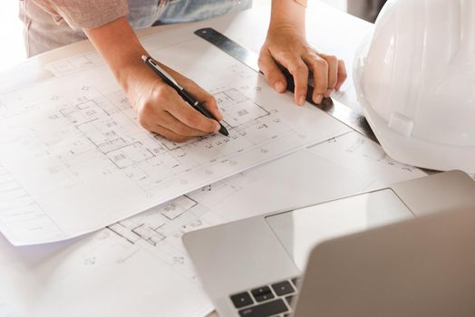 Top view of Engineer or architect holding pen with drawings in construction on blueprints in office. Engineering and construction concept.