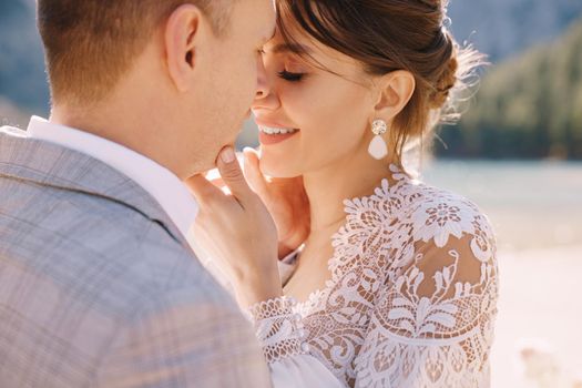 Newlyweds kiss on the spot for the ceremony, with an arch of autumn flower columns, against the backdrop of Lago di Braies in Italy. Destination wedding in Europe, at Braies lake.