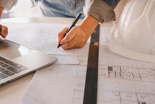Engineers holding a pen pointing to a building and drawing outlay construction plan as guide for builders with details.Engineering and construction concept.