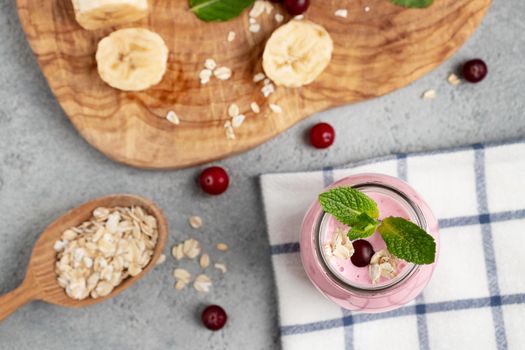 Homemade yogurt smoothie with banana, cranberry and oatmeal, top view, flat lay.