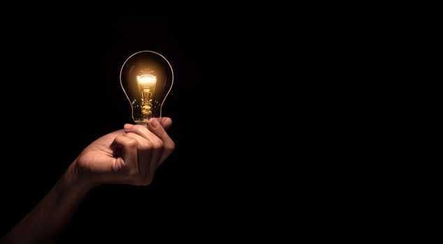 Hand a light bulb isolate on black background.Energy or idea concept