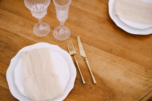 White plates on a wooden table, serving a table for a wedding dinner.