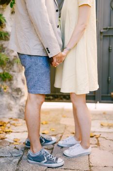 Man and woman are standing on the street holding hands, close-up . High quality photo