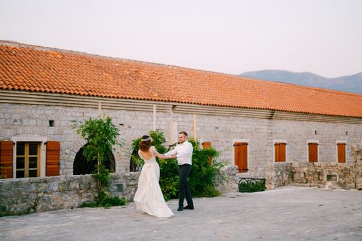 The bride and groom whirl, holding hands, near the church in the old town of Budva . High quality photo