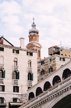 The beautiful Ponte di Rialto Bridge over Central Grand Canal in Venice, Italy, with shops, beautiful views and lots of people. Near boat station of the same name, the street leads to San Marco