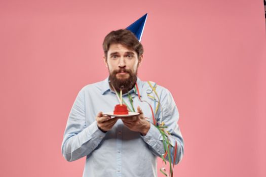 Birthday of a man with a cake and with a candle on a pink background. High quality photo