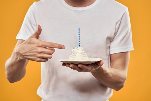 A man with a birthday cake in his hands on a yellow background birthday dessert. High quality photo