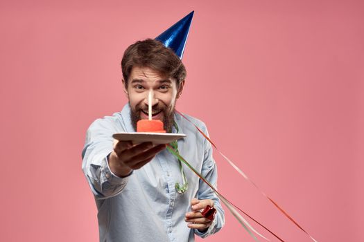 Bearded man with cake tongue on a pink background cropped view and a blue cap on his head. High quality photo