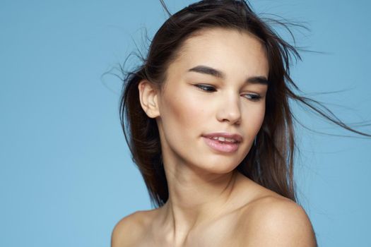Woman with naked shoulders long hair cosmetics attractive look blue background. High quality photo
