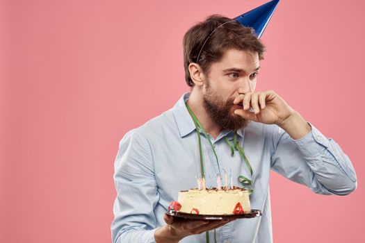 Bearded man with cake on pink background birthday party corporate emotions model loneliness. High quality photo