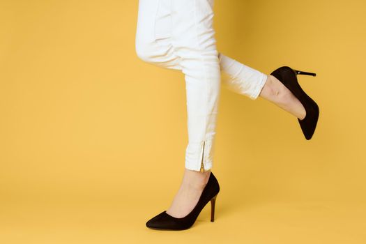 Woman in black shoes legs clipped lit yellow background fashion shopping. High quality photo