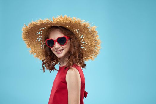 Girl in a beach Straw hat in sunglasses curly hair fun blue background. High quality photo