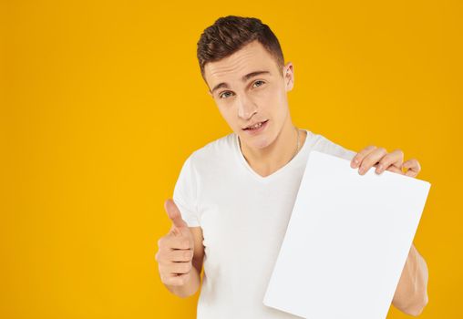 Guy with white sheet of paper mockup yellow background Copy Space. High quality photo