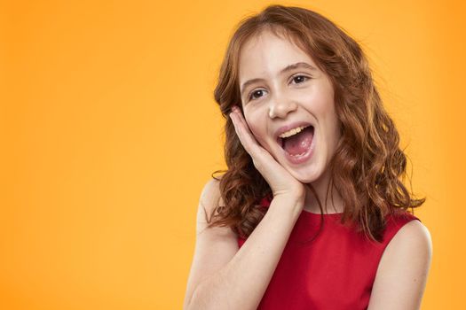 Girl with curly hair red dress fun childhood emotions yellow background. High quality photo